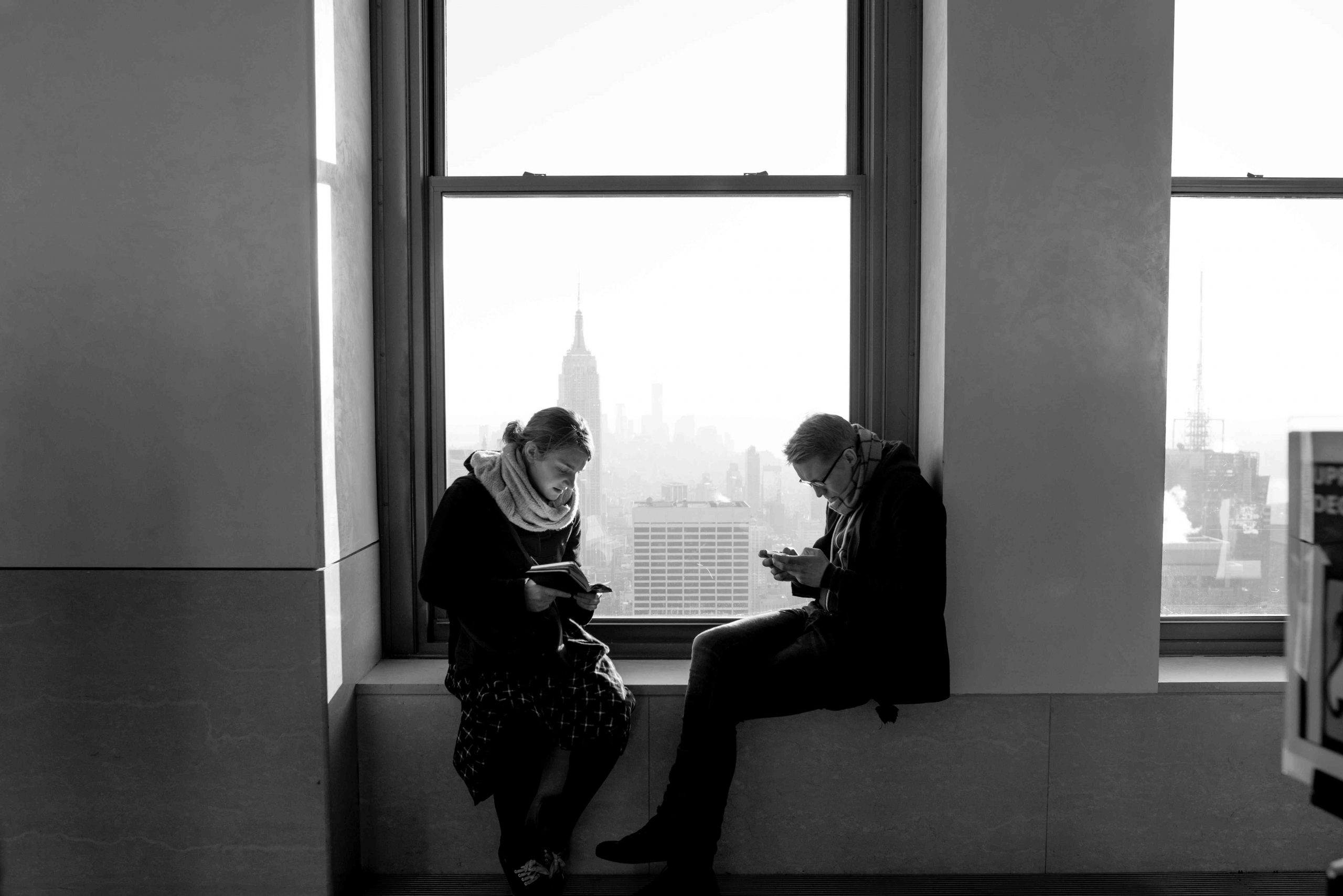 Zwei Menschen sitzen sich gegenüber und schauen gebannt auf ihr Smartphone